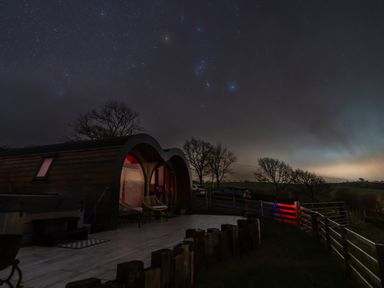 A curved wooden cabin with chairs outside under a starry night sky at Creuddyn in Llanfihangel-y-Creuddyn near Aberystwyth