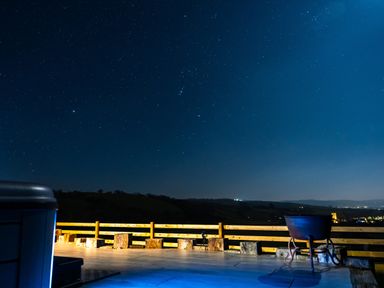 An outdoor area with a chair and hot tub under a starry sky at Creuddyn in Llanfihangel-y-Creuddyn near Aberystwyth