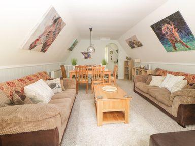 A living room with brown sofas a wooden coffee table and a dining table with chairs at 17 Valley Lodges in Gunnislake