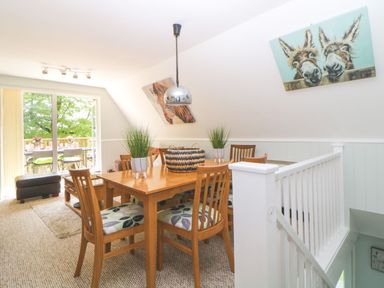 A dining area with a wooden table and chairs next to a glass door leading to a balcony at 17 Valley Lodges in Gunnislake