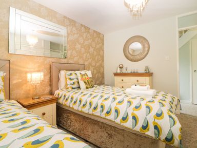 A bedroom with two single beds bedside table dresser and mirrors at 17 Valley Lodges in Gunnislake