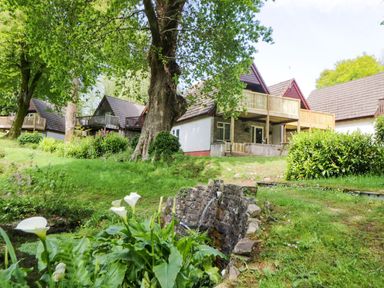 Exterior of lodges with balconies surrounded by trees green grass and plants at 17 Valley Lodges in Gunnislake