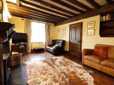 A living room with wooden beams on the ceiling and a cowhide rug on the floor at Gwengraig in Brithdir near Dolgellau