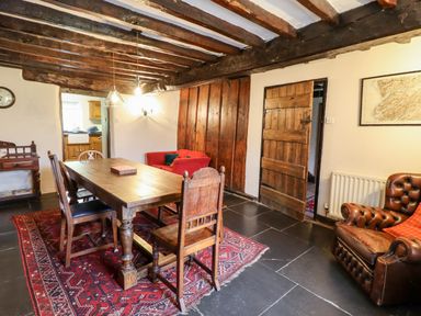 A dining room with a wooden table and chairs a red rug and a brown leather armchair at Gwengraig Brithdir near Dolgellau