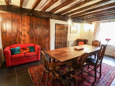 A dining room with a wooden table and chairs a red sofa and a leather armchair at Gwengraig Brithdir near Dolgellau