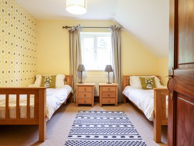 A bedroom with two single beds a patterned rug and nightstands with lamps at Gwengraig in Brithdir near Dolgellau