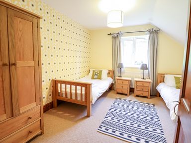 A bedroom with two single beds a wardrobe two bedside tables and a patterned rug at Gwengraig in Brithdir near Dolgellau
