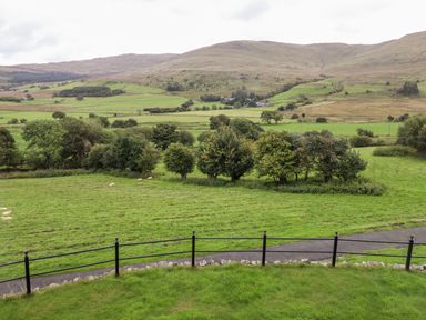 A rural landscape with green fields trees sheep and hills in the background at Gwengraig in Brithdir near Dolgellau