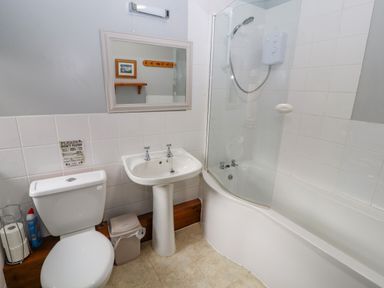 A bathroom with a toilet, sink, and bathtub with a shower at Old School Muncaster House in Ravenglass near Holmrook