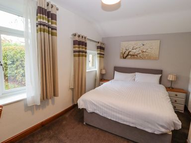 A bedroom with a double bed two bedside tables lamps and curtains at Old School Muncaster House Ravenglass near Holmrook