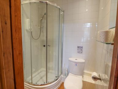 A bathroom with a corner shower enclosure and a toilet with toilet paper at Old School Muncaster House Ravenglass near Holmrook