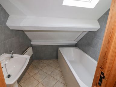 A bathroom with a bathtub sink and small window at Old School Muncaster House in Ravenglass near Holmrook