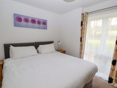 A bedroom with a double bed two bedside tables lamp and a window with curtains at Old School Muncaster House Ravenglass near Holmrook