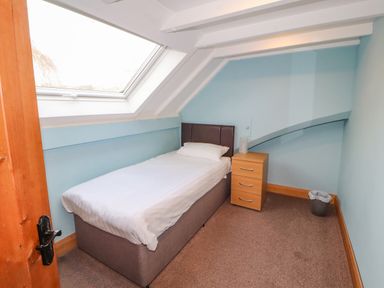 A bedroom with a single bed next to a bedside table and a window in the ceiling at Old School Muncaster House Ravenglass near Holmrook