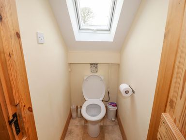 A small bathroom with a toilet a waste bin and a skylight window at Old School Muncaster House in Ravenglass near Holmrook
