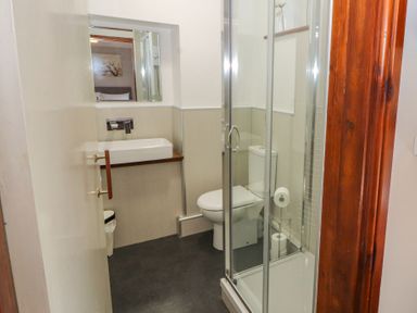 A small bathroom with a shower enclosure toilet and sink at Old School Muncaster House Ravenglass near Holmrook