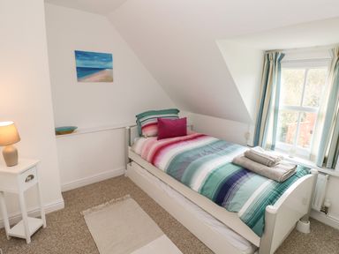 A single bed with striped bedding and a pillow next to a window in a bedroom at North Studdock Cottage Angle near Pembroke