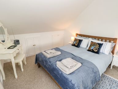 A bedroom with a double bed and bedside tables with lamps and a dressing table at North Studdock Cottage in Angle near Pembroke