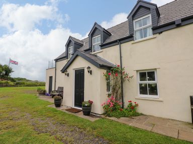A house with a black door and flowers in planters at North Studdock Cottage, Angle near Pembroke