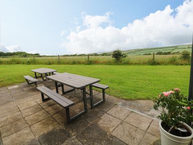 A table and benches on a patio area at North Studdock Cottage in Angle near Pembroke