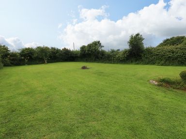 A garden with grass and a fire pit at North Studdock Cottage, Angle near Pembroke