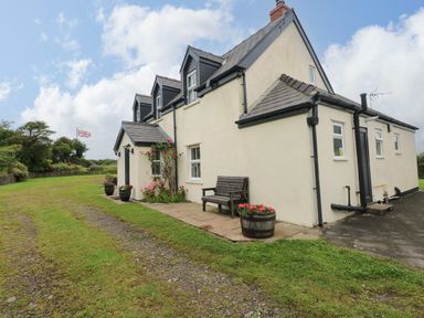 An outdoor view of a house with a bench and flower pots at North Studdock Cottage Angle near Pembroke