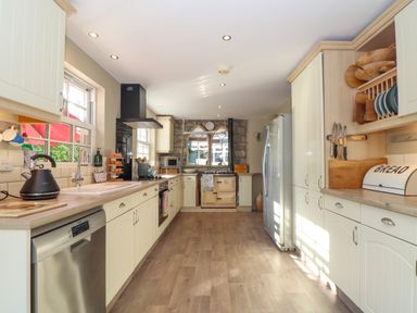 A kitchen with white cabinets a dishwasher and a refrigerator at Lower Gadles in Burnthouse near Falmouth