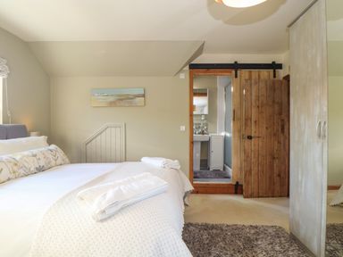 A bedroom with a bed towel and a wooden sliding door leading to a bathroom at Lower Gadles Burnthouse near Falmouth