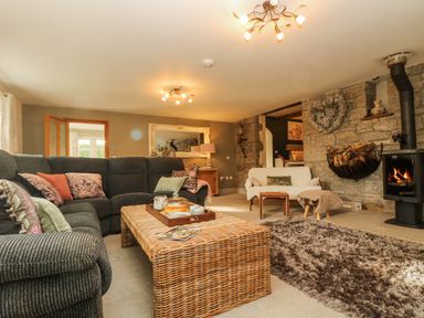 A living room with a gray sofa and a wicker coffee table near a fireplace at Lower Gadles Burnthouse near Falmouth