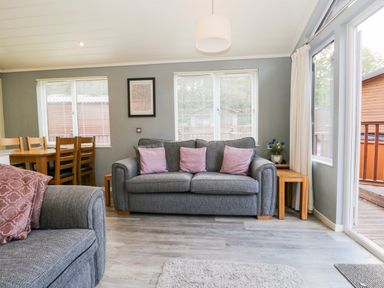 A living room with two gray sofas and purple cushions at Wansfell Lodge Pony Meadow 36 White Cross Bay near Windermere