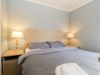 A bedroom with a bed covered with gray bedding two bedside tables and lamps with gray walls at Wansfell Lodge Pony Meadow 36 White Cross Bay near Windermere