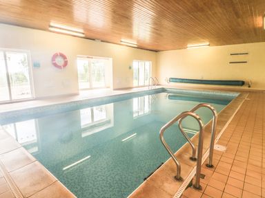 An indoor swimming pool with metal handrails and a tiled floor at The Coach House in St Florence