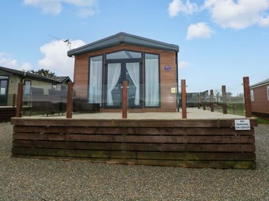 A cabin with a deck and glass railing at Oyster Lodge in Little Haven
