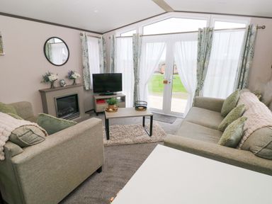 A living room with sofa and television at Oyster Lodge in Little Haven