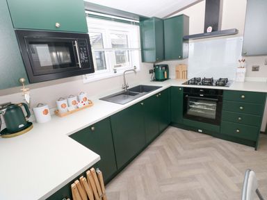 A kitchen with cabinets, sink, stove, and microwave at Oyster Lodge Little Haven