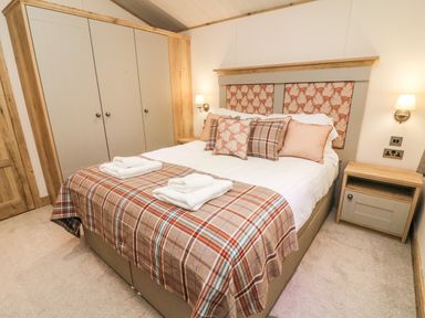 A bedroom with a bed pillows bedside tables lamps and built in wardrobes at Coniston View 9 Dock Acres near Tewitfield