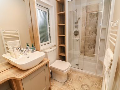 A bathroom with a sink, toilet, shower, window, and towel racks at Coniston View 9 Dock Acres near Tewitfield