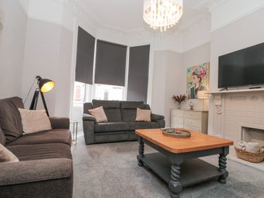 A living room with two sofas a wooden coffee table a fireplace and a television at Westbourne House in Scarborough