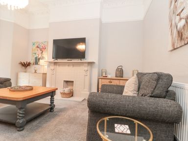 A living room with a television above a fireplace and a coffee table at Westbourne House in Scarborough