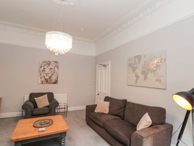 A living room with dark sofas a wooden coffee table and wall art at Westbourne House in Scarborough