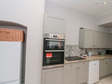 A kitchen with built-in double oven stove kettle refrigerator and patterned tile backsplash at Westbourne House in Scarborough