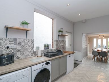 A kitchen with washing machine dishwasher toaster and plants leading to a dining area at Westbourne House in Scarborough
