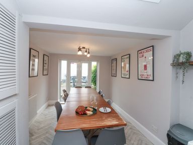A dining room with a long wooden table surrounded by chairs and framed posters on the walls at Westbourne House in Scarborough