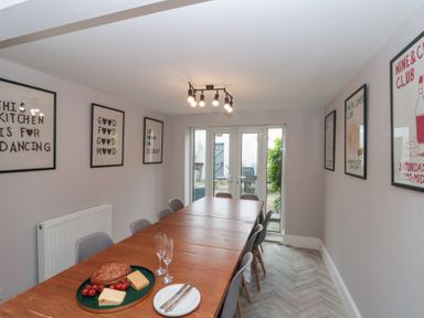 A dining room with a long wooden table surrounded by chairs and decorative wall art at Westbourne House in Scarborough