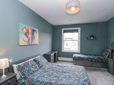 A bedroom with two beds a desk a nightstand and a window at Westbourne House Scarborough