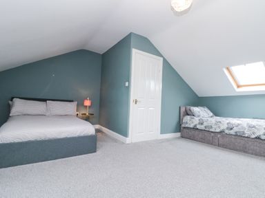 A bedroom with two beds a small bedside table with a lamp and a skylight window at Westbourne House in Scarborough