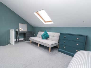 A room with a sofa bed a chest of drawers and a desk under a skylight at Westbourne House in Scarborough