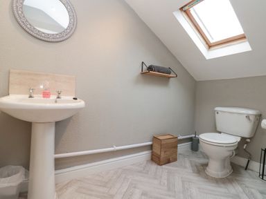 A bathroom with a pedestal sink and mirror towel on a wall shelf a skylight window and a toilet at Westbourne House Scarborough