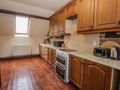 A kitchen with wood flooring wood cabinets a stove a toaster a kettle a microwave and a skylight window at Owlbury Hall Barn in Snead near Bishop's Castle Montgomery