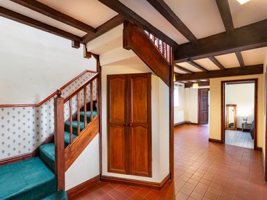 An entryway with wooden staircase green carpet and terracotta tiled floor at Owlbury Hall Barn Snead near Bishops Castle Montgomery